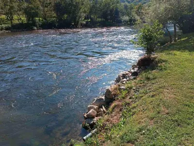a river with rocks on the side of a field at Villa ADA in Jajce