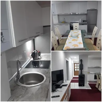 a kitchen with white cabinets and a sink and a table at AQUA VET Velika Kladuša in Velika Kladuša