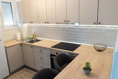 a kitchen with white cabinets and a wooden counter top at Lux Apartment III Prijedor in Prijedor