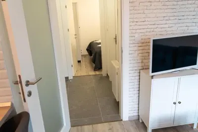 a hallway with a brick wall and a flat screen tv at Lux Apartment III Prijedor in Prijedor