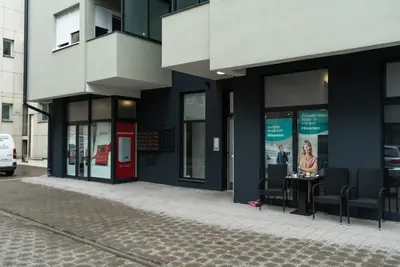 a woman sitting at a table outside of a building at Lux Apartment III Prijedor in Prijedor