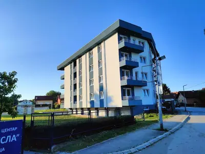 a large white building with a black roof at Apartman Centar Kozarska Dubica in Bosanska Dubica