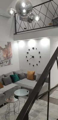 a living room with a couch and a clock on the wall at Central Maisonette in Banja Luka