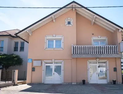 a pink house with white doors and a balcony at GOOD People in Bihać