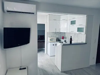 a kitchen with white cabinets and a flat screen tv at Stan 7 in Kiseljak