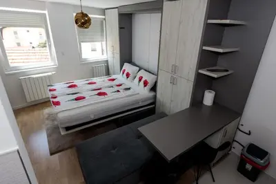 a small room with a bed and a desk at Apartman Skver in Tuzla