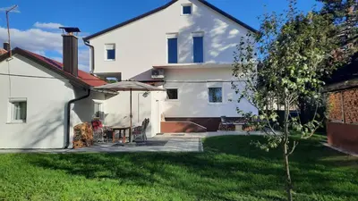 a white house with a table and an umbrella at 7 Kućica in Livno