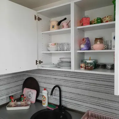 a kitchen counter with a sink and shelves with dishes at Apartman Nira in Zenica