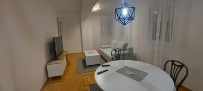 a living room with a white table and a television at Apartmani ANNA in Banja Luka