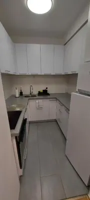 a kitchen with white cabinets and a sink and a refrigerator at Apartmani ANNA in Banja Luka