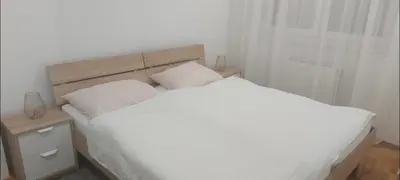 a bedroom with a white bed with a wooden headboard at Apartmani ANNA in Banja Luka