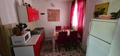 a kitchen with a table with red cabinets and a microwave at Apartman Hushida in Bihać