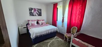 a small bedroom with red curtains and a bed at Apartman Hushida in Bihać