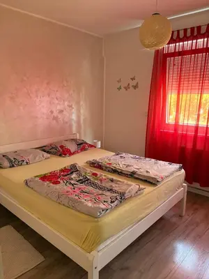 a bed in a bedroom with a red window at Apartman VIVA in Bihać