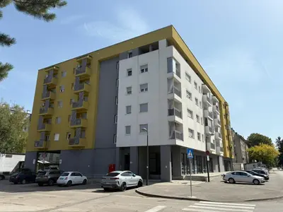 a building with cars parked in a parking lot at Apartman VIVA in Bihać