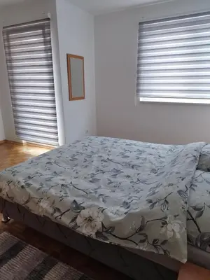 a bed in a bedroom with two windows at Apartman Sandi in Novi Travnik
