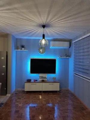 a living room with a tv and a blue wall at Apartman Sandi in Novi Travnik