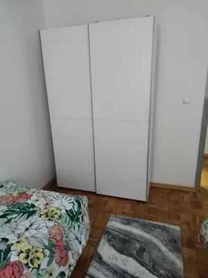 two white cabinets in a room with a bed and a rug at Apartman Sandi in Novi Travnik