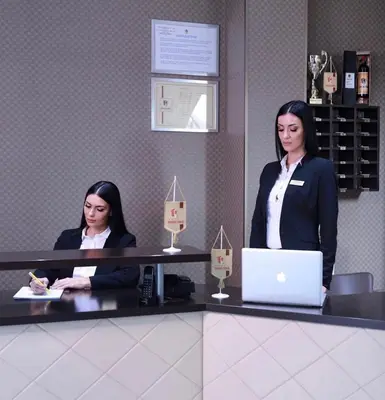 two women sitting at a counter with a laptop at Hotel Banja Luka in Banja Luka
