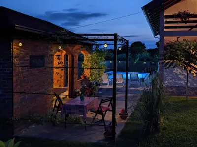 a patio with a table in the yard at night at Wisteria Lodge in Derventa