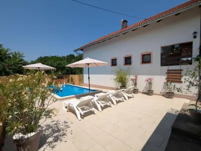 a patio with chairs and an umbrella and a pool at Wisteria Lodge in Derventa
