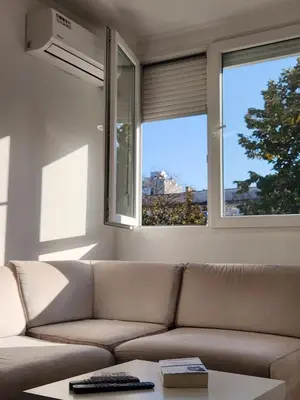 a living room with a couch and two windows at Stan na dan Nova Varoš in Banja Luka