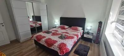 a bedroom with a bed with a red and white comforter at LARA S in Banja Luka