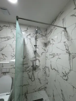 a shower in a bathroom with a marble wall at Aparmani Karanovic in Zavidovići