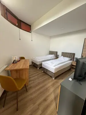 a room with two beds and a desk and a television at Aparmani Karanovic in Zavidovići