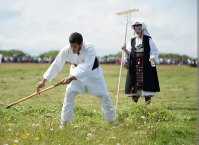 a man and woman in a field playing with a stick at Kupres, centar, apartman in Kupres