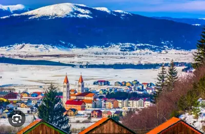 a city with a snowy mountain in the background at Kupres, centar, apartman in Kupres