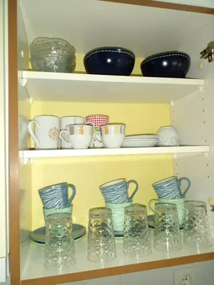 a shelf filled with bowls and cups and plates at Stan na dan Apartman Kozarac in Kozarac