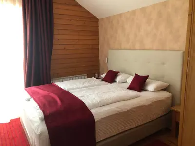 a bedroom with a large white bed with red pillows at Pansion Vlašić Ski in Šišava
