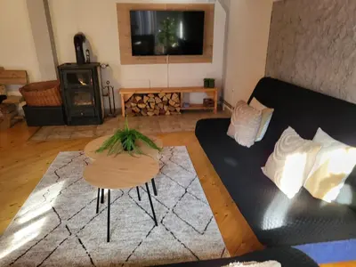 a living room with a black couch and a table at Cozy Cottage Vlašić in Vlasic