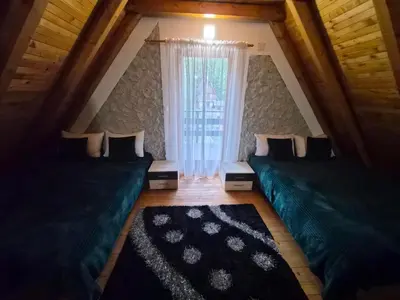 a attic room with two beds and a window at Cozy Cottage Vlašić in Vlasic