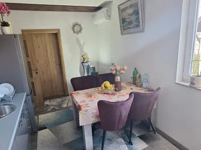 a kitchen table with purple chairs and a table with flowers on it at Apartmani Villas in Visoko