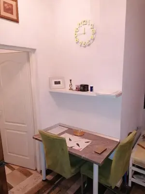 a dining room table and chairs with a clock on the wall at Apartmani Milica in Banja Luka