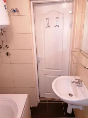 a white bathroom with a sink and a shower at Apartmani Milica in Banja Luka