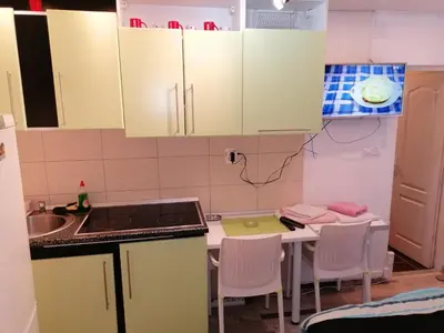 a kitchen with white cabinets and a table with chairs at Apartmani Milica in Banja Luka