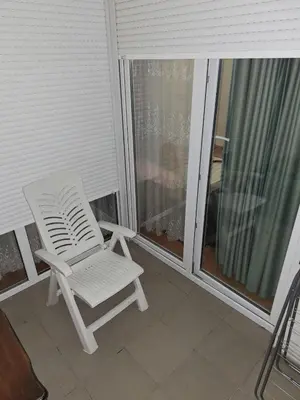 a white chair sitting on a porch next to a window at Elegantna oaza apartment in Banja Luka