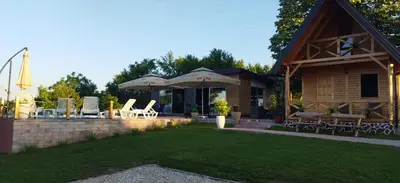 a house with a patio with chairs and an umbrella at Koliba La Perla in Banja Luka