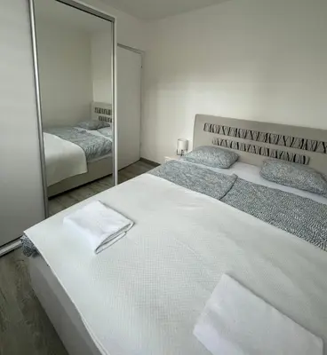 a bedroom with a large white bed and a mirror at Apartman “ Ismar “ in Travnik