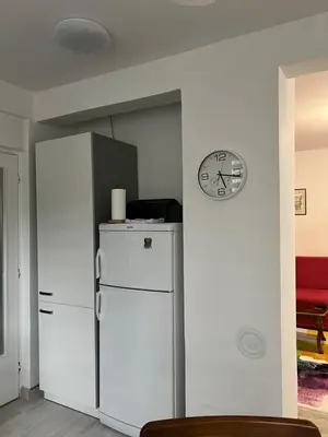 a kitchen with a refrigerator and a clock on a wall at Apartman “ Ismar “ in Travnik