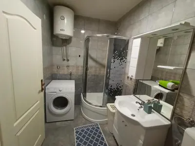 a bathroom with a shower sink and a washing machine at Apartmani Vesna in Banja Luka