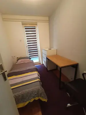 a small room with a bed and a desk and a window at Apartmani Vesna in Banja Luka