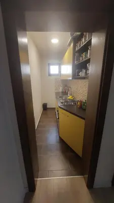 a small kitchen with yellow cabinets and a tile floor at AS Apartman Visoko in Visoko