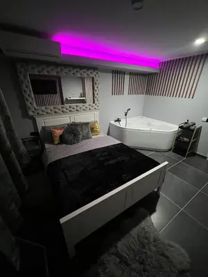 a bedroom with a bed and a bath tub and pink lights at Apartman Banja Luka CITY in Banja Luka