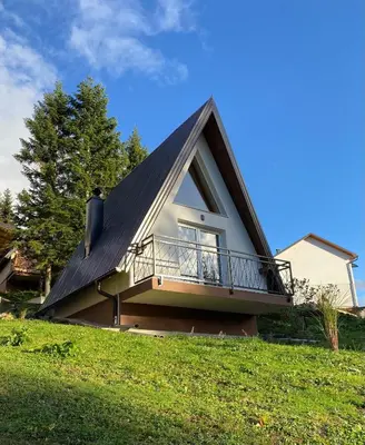 a house with a gambrel roof with a balcony at Alpi Cabin Pridolci in Busovača