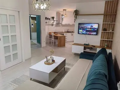 a living room with a blue couch and a kitchen at APARTMAN ANIKA - STAN NA DAN Doboj in Doboj