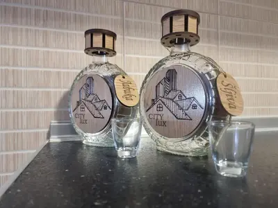 two glass bottles sitting on a table with glasses at CityLux Doboj in Doboj